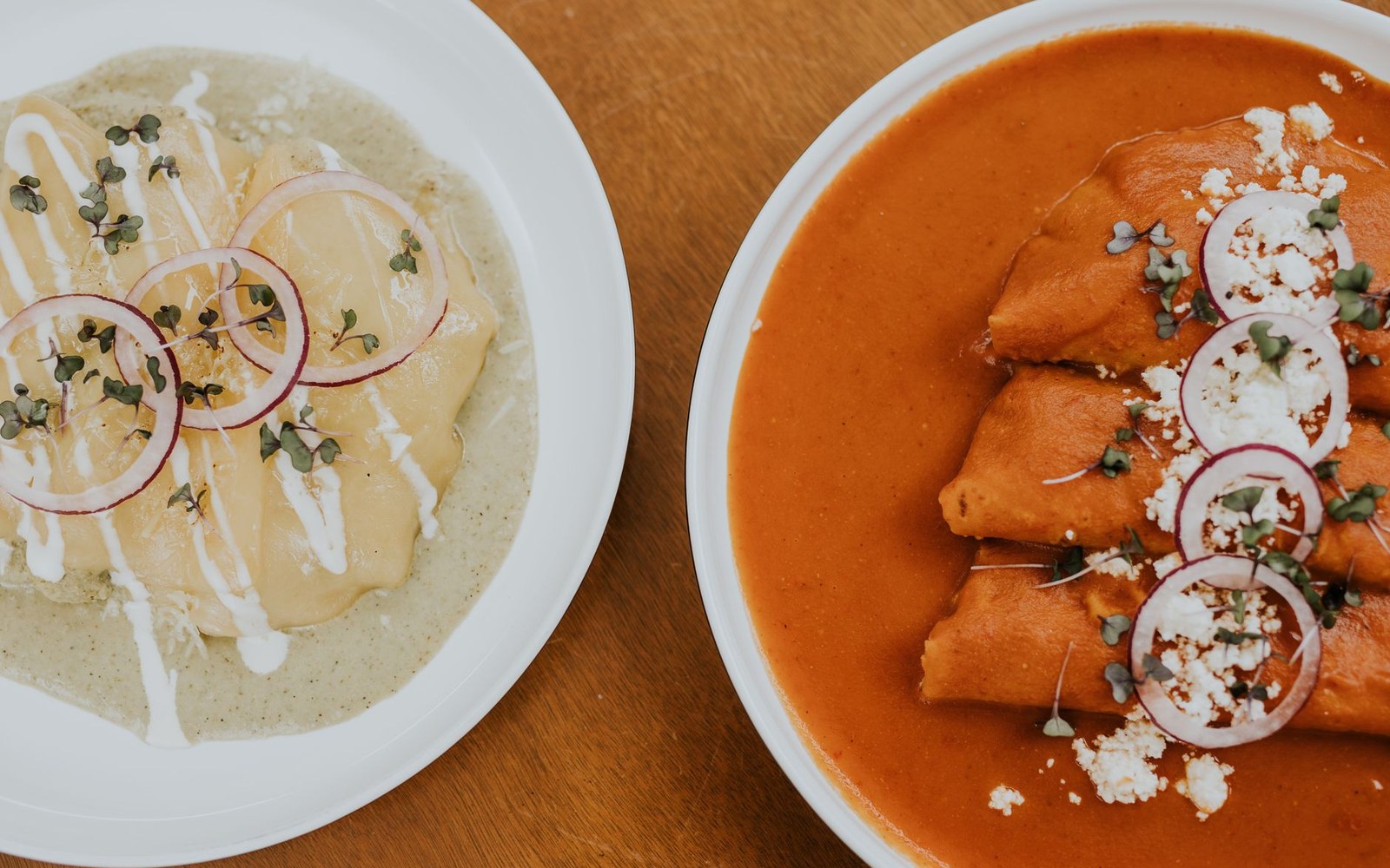 Two plates of enchiladas, one topped with green sauce and one with red chile sauce