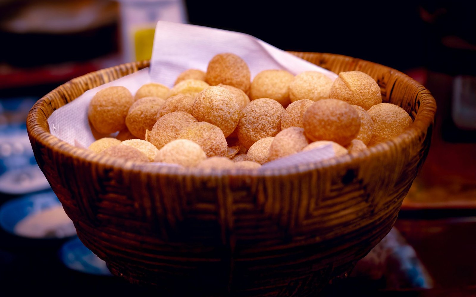 Woven basket lined with cloth holding a pile of golden fried sopaipillas