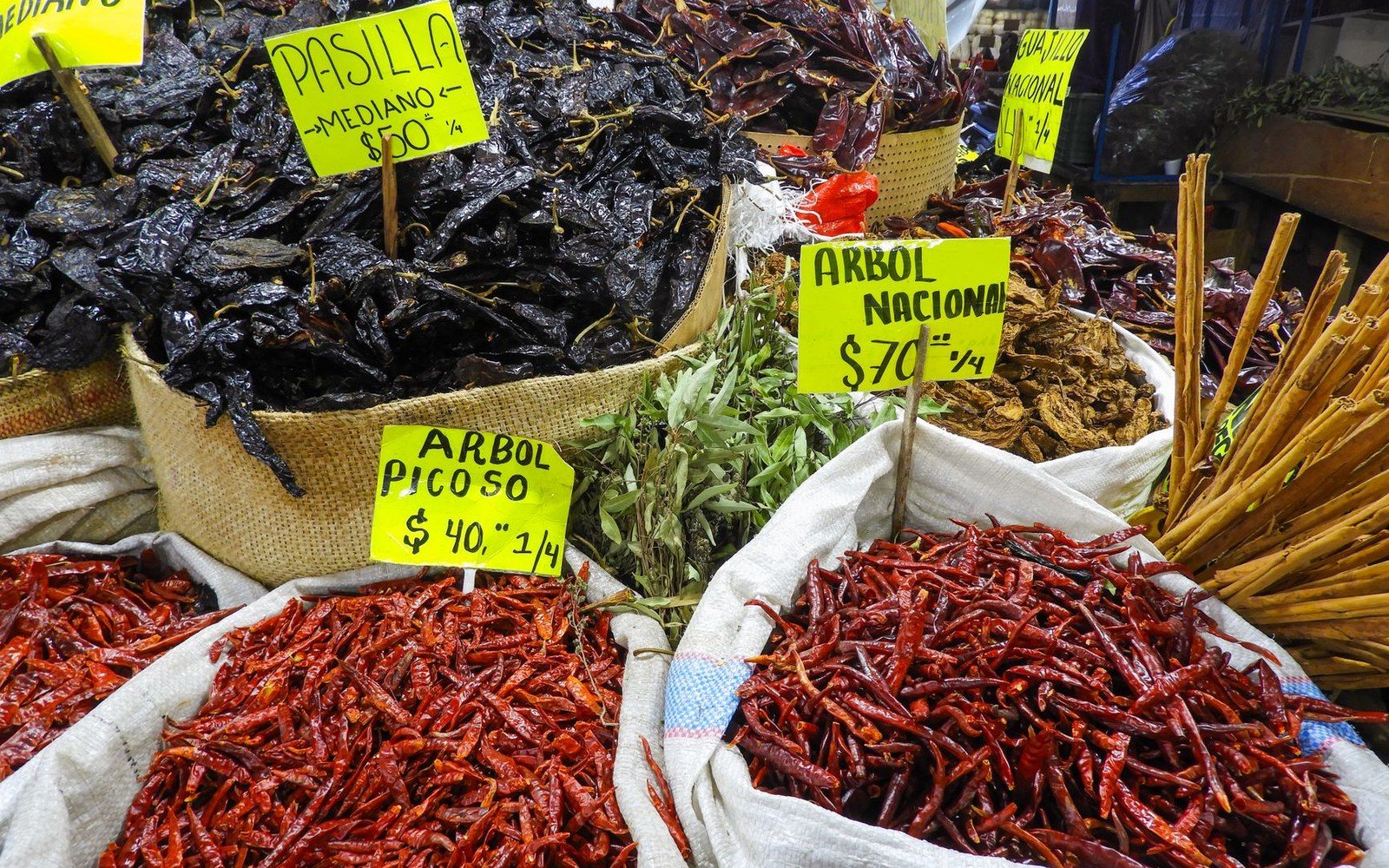 A ristra of dried red chile pods against a mud-plastered adobe wall, close enough that the pods fill the frame